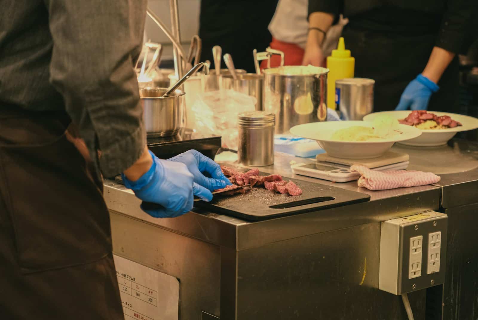 Cocinero con guantes desechables preparando alimentos en una cocina profesional