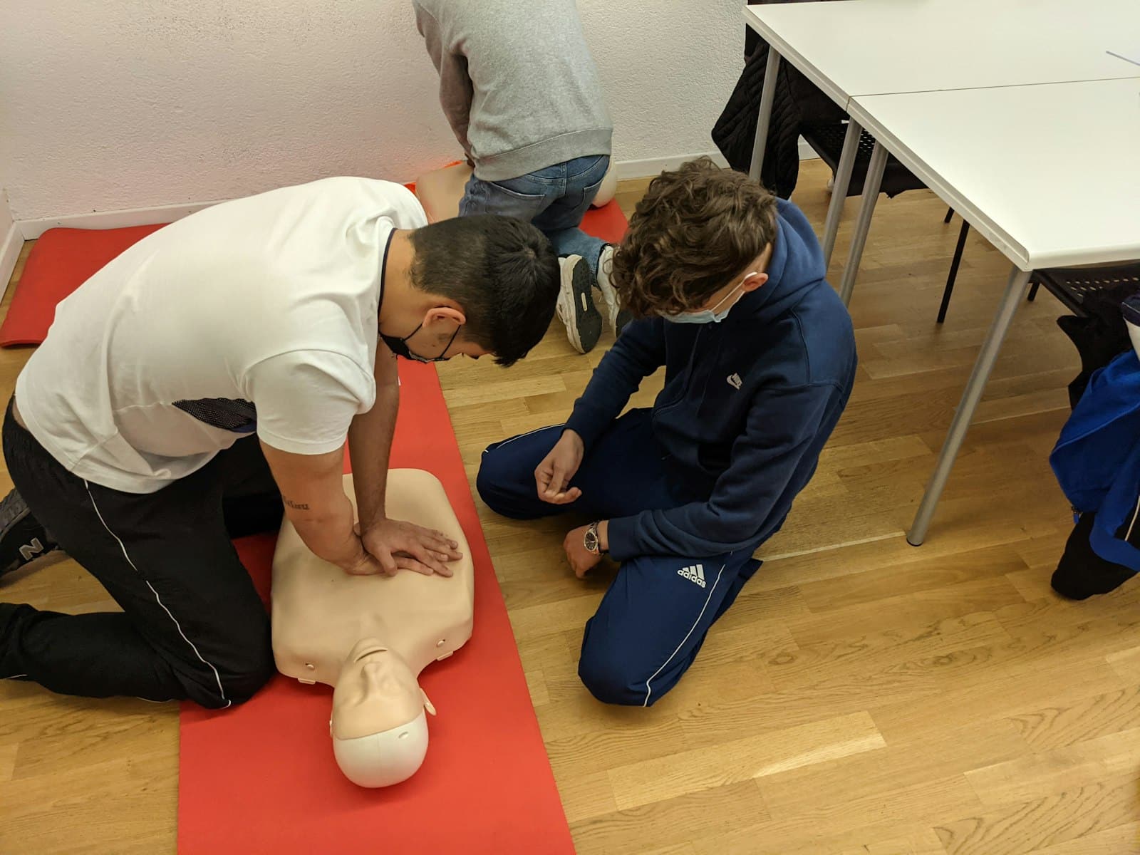 Alumnos practicando compresiones torácicas de RCP sobre un maniquí en un aula de formación
