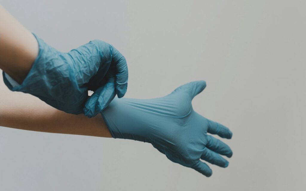 Manos poniéndose guantes de nitrilo azules antes de un tratamiento