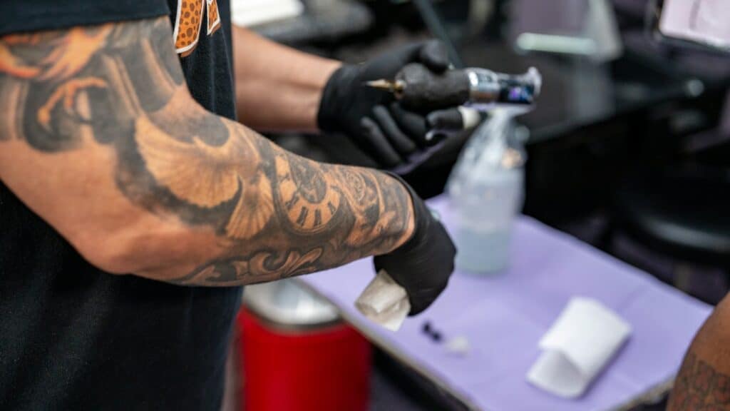 Tatuador con guantes preparando el material sobre una superficie protegida con film